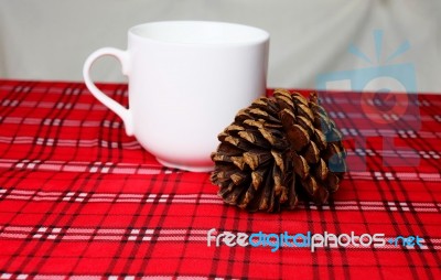 Warm Drink, White Mug And Pine Cone On Red Table Cloth (front Fo… Stock Photo