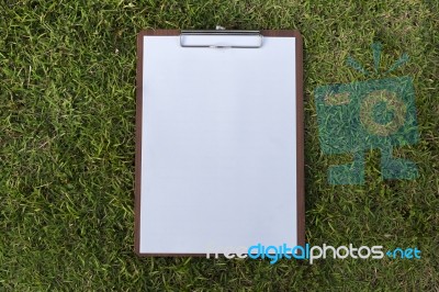 White Paper On Wooden Clipboard On Green Grass Background Stock Photo