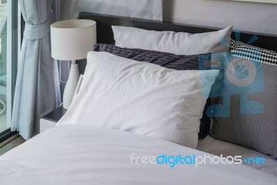White Pillow In Modern Bedroom With White Lamp On Table Stock Photo
