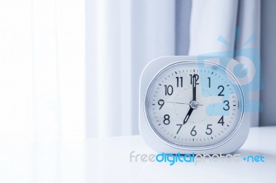 White Square Clock On White Bed Stand With White Curtain Background, Morning Time In Minimal Style Decoration Stock Photo