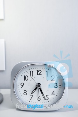 White Square Clock On White Bed Stand With White Wallpaper Background, Morning Time In Minimal Style Decoration Stock Photo