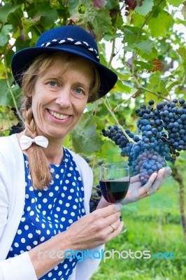 Woman Holding Glass Of Wine Near Bunch Of Blue Grapes Stock Photo