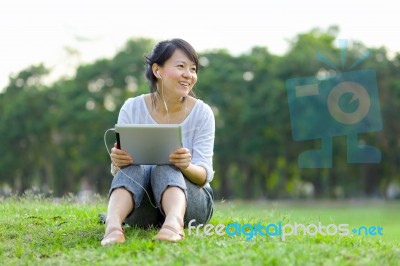 Woman Holding Tablet In Park Stock Photo