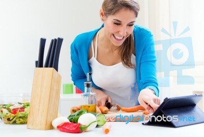 Woman In Kitchen Looking For A Recipe On The Internet Stock Photo