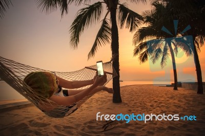 Woman Lying In Beach Cradle And Taking A Photograph By Smart Phone Stock Photo