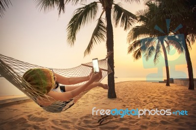Woman Lying In Beach Cradle And Taking A Photograph By Smart Phone Stock Photo