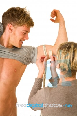 Woman Measuring Biceps Of Young Man Stock Photo