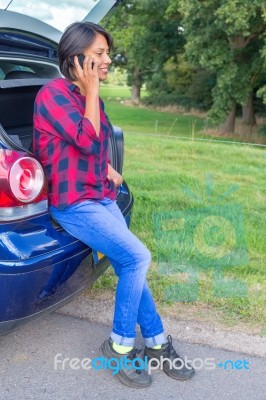 Woman Phoning Mobile Sitting In Car Trunk Outside Stock Photo