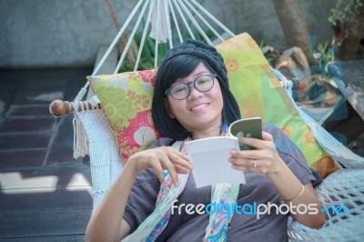 Woman Reading Book On Cradle Stock Photo