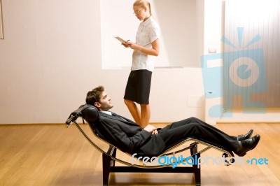 Woman Reading Man Lying On Chaise Longue Stock Photo