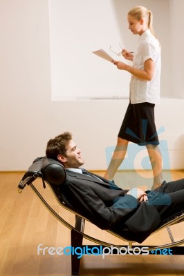 Woman Reading Man Lying On Chaise Longue Stock Photo