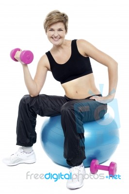 Woman Seated On Fitness Ball Doing Dumbbells Stock Photo
