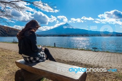 Woman Sitting On A Bench At Kawaguchiko Lake, Japan. View Of Fuji Mountains Stock Photo