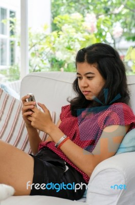 Woman With Her Smart Phone Sitting On Sofa In Living Room Stock Photo