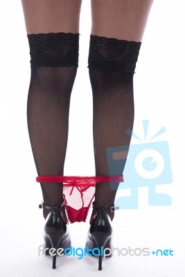 Woman's Legs With Fishnet Stockings And Red Slip Stock Photo