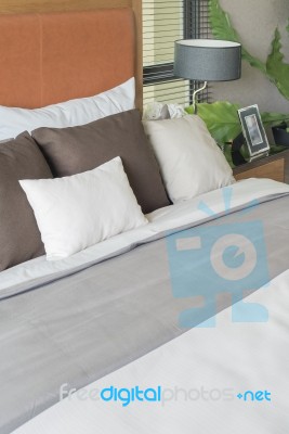 Wooden Bed With White And Brown Pillows In Bedroom Stock Photo