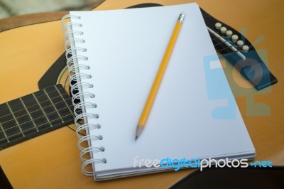 Yellow Acoustic Guitar On Wooden Table Stock Photo