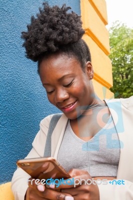 Young African Woman Chatting With Her Smartphone Stock Photo
