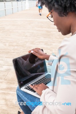 Young African Woman Typing On Her Laptop Stock Photo