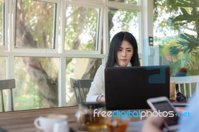 Young Asian Woman Working With Laptop In Coffee Shop Stock Photo