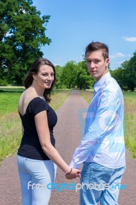 Young Attractive Caucasian Couple Hand In Hand Looking Back Stock Photo