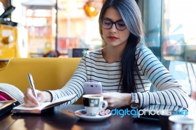 Young Beautiful Woman Using Her Mobile Phone In Coffee Stock Photo