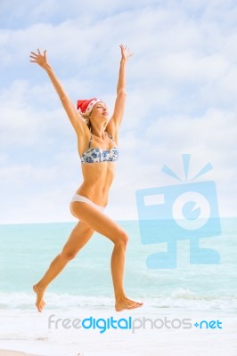 Young Blonde Woman In Bikini And Christmas Santa Hat Jumping On Stock Photo