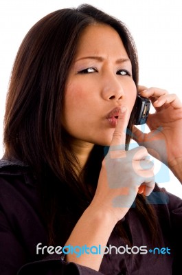 Young Corporate Woman Talking On Cell Phone And Shushing Stock Photo