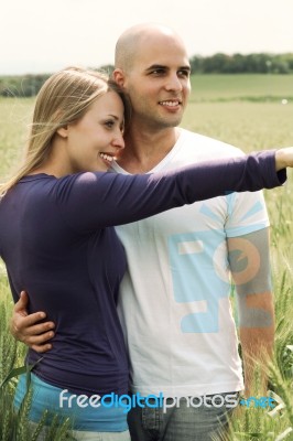 Young Couple In Meadow With The Hands In The Air, Hugging Stock Photo