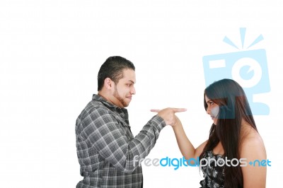 Young Couple Pointing At Each Other Against A White Background Stock Photo