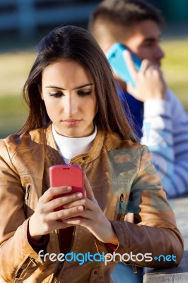 Young Couple With Smartphones In The Park Stock Photo Young Couple With Smartphones In The Park Stock Photo