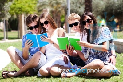 Young Couples Relaxing In Park And Reading Books Stock Photo
