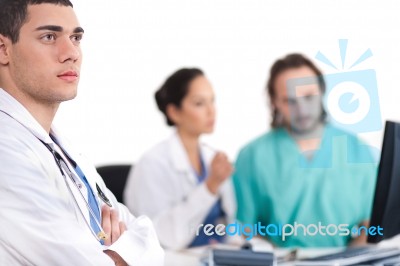 Young Doctor Thinking, Collegues Discussing Behind With Computer… Stock Photo