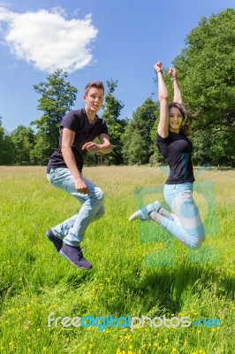Young Dutch Couple Jumping In Green Meadow Stock Photo