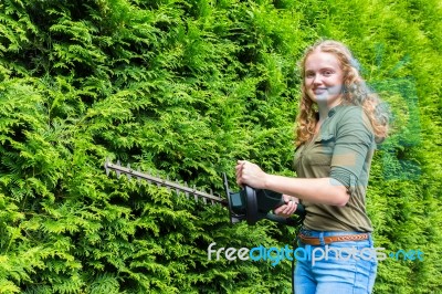 Young Dutch Woman Holding Hedge Trimmer At Conifers Stock Photo