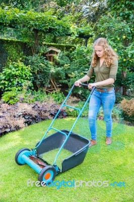 Young Dutch Woman Pushing Lawn Mower On Grass Stock Photo