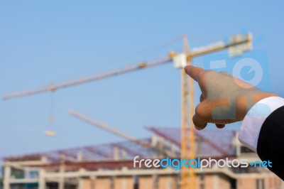 Young Engineer In Orange Shirt Stands Pointing At A Building Bei… Stock Photo