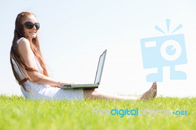 Young Feamle Sit In The Park And Using A Laptop Stock Photo