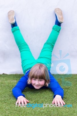 Young Girl Lying Upside Down Against Wall Stock Photo