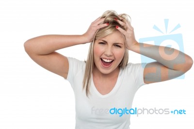 Young Girl Screaming Loud While Holding Her Head Stock Photo
