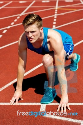 Young Male Sprinter In Starting Blocks Stock Photo