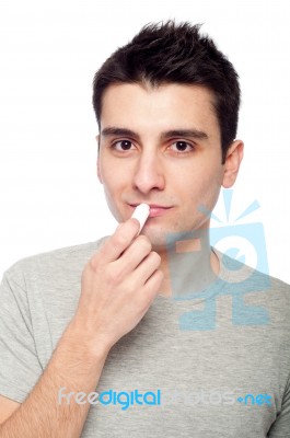 Young Man Applying Lip Balm Stock Photo