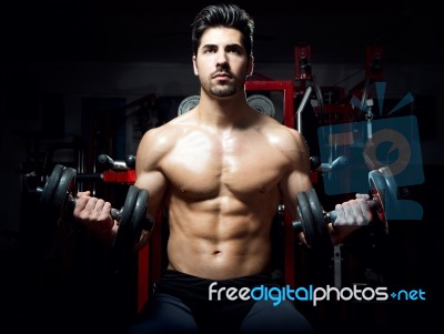 Young Man Doing Heavy Weight Exercise In Gym Stock Photo