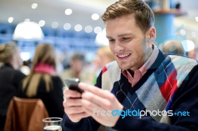 Young Man In Cafe And Using His Mobile Phone Stock Photo