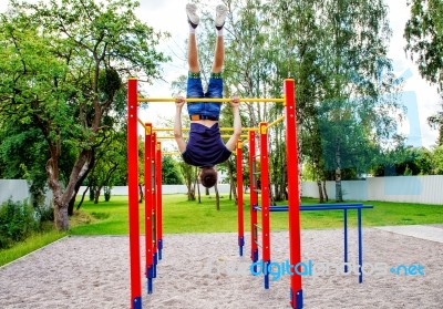 Young Man Is Practicing On A Horizontal Bar Stock Photo
