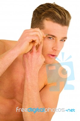 Young Man Tweezing Eyebrows Stock Photo