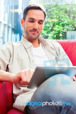 Young Man Using Digital Tablet On Sofa Stock Photo