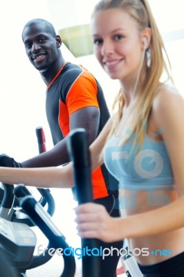 Young People With Elliptic Machine In The Gym Stock Photo