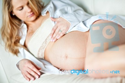 Young Pregnant Woman Resting On Sofa Stock Photo