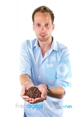 Young Salesman Showing Hands Full With Coffee Beans Stock Photo
